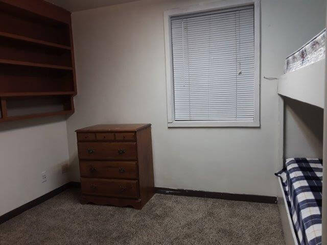 Shared-bedroom 2 showing built-in bookshelves, dresser, large window, and built-in bunk-beds with twin mattresses.