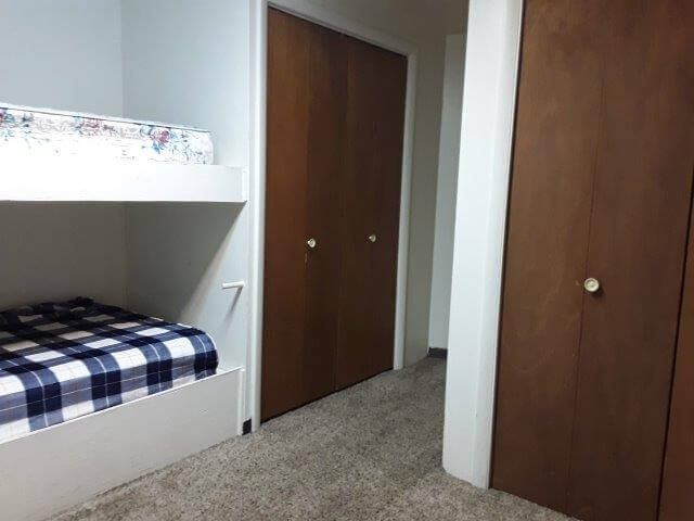 Shared-bedroom 2 showing built-in bunk-beds with twin mattresses and two closets with bifold doors.