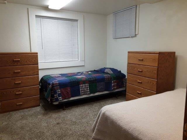 Shared-bedroom 1 showing two twin beds, two 5-drawer dressers, a large and a small window.